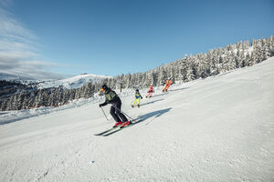 A group of skiers enjoys the descent in the snow. | © Korbinian Seifert