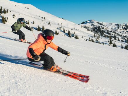 Zwei Skifahrer auf einer verschneiten Piste in den Bergen. | © Mr. Offenblende