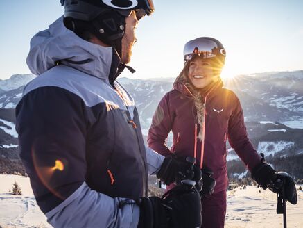 Ein lächelndes Paar im Schnee, bereit zum Skifahren.