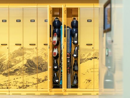 Opened yellow ski locker with skis and helmets. | © Johannes Radlwimmer